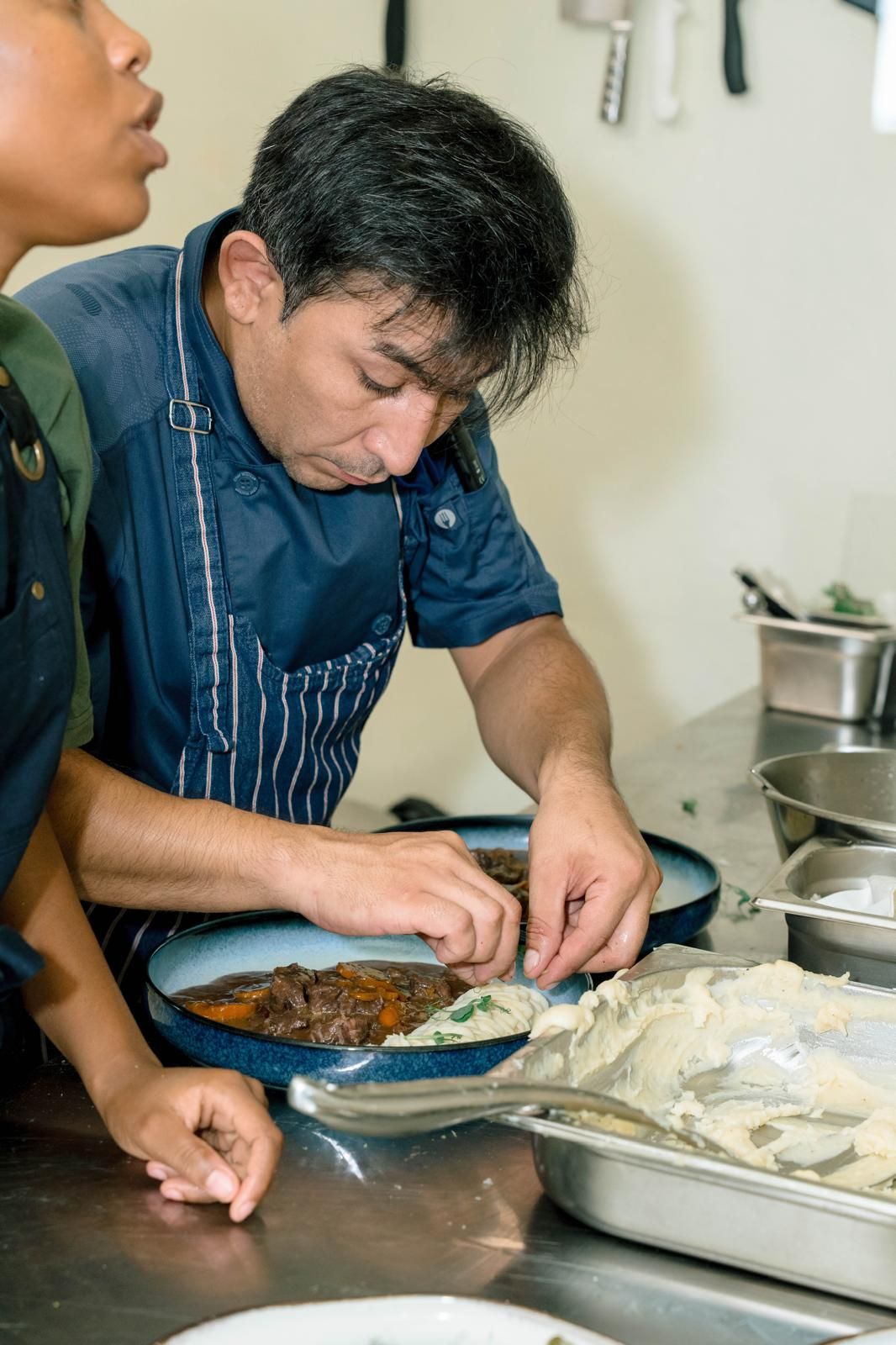 Cocinero preparando un plato en la cocina del restaurante