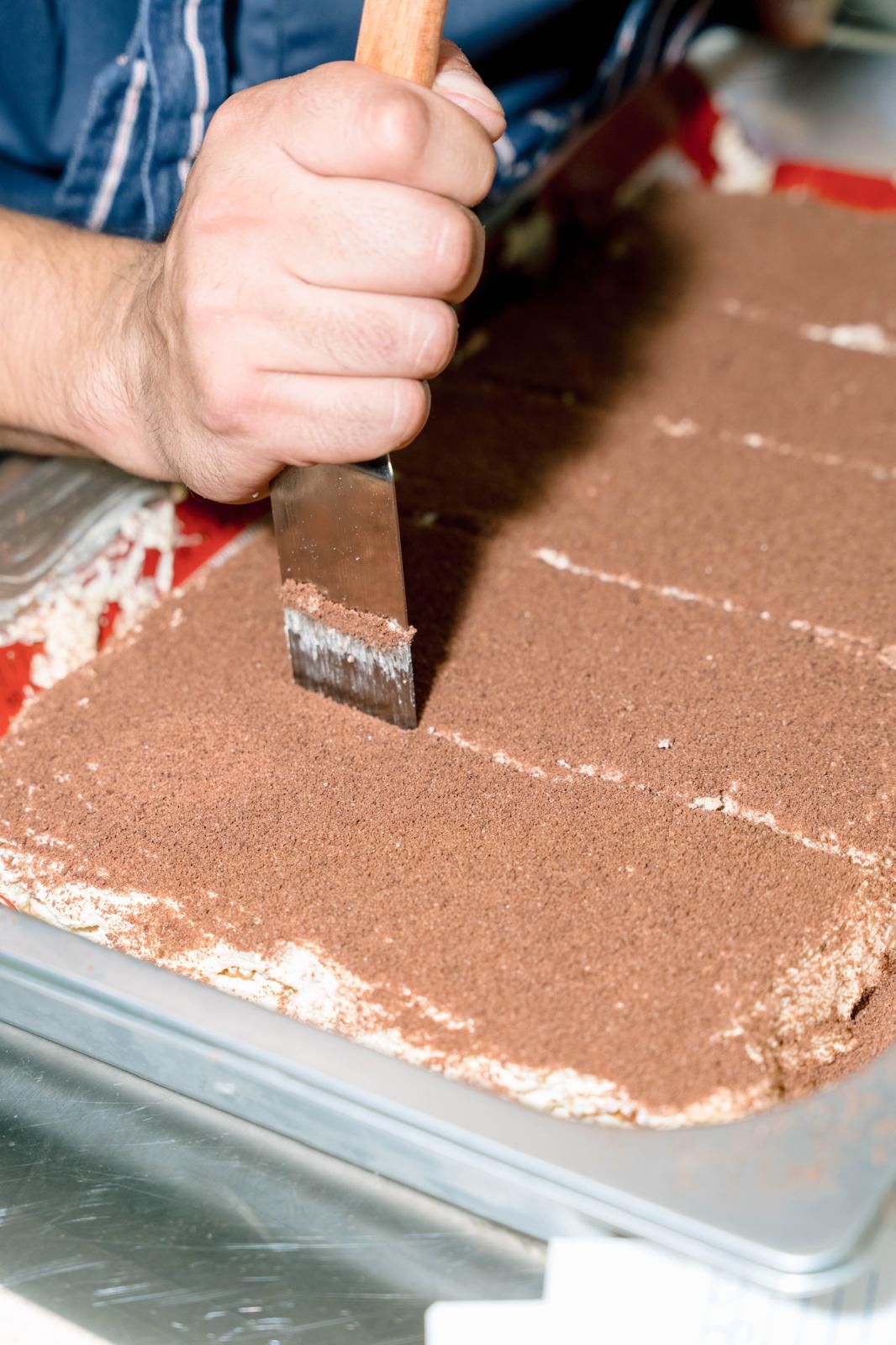 Espolvoreando cacao sobre un postre recién montado en la cocina