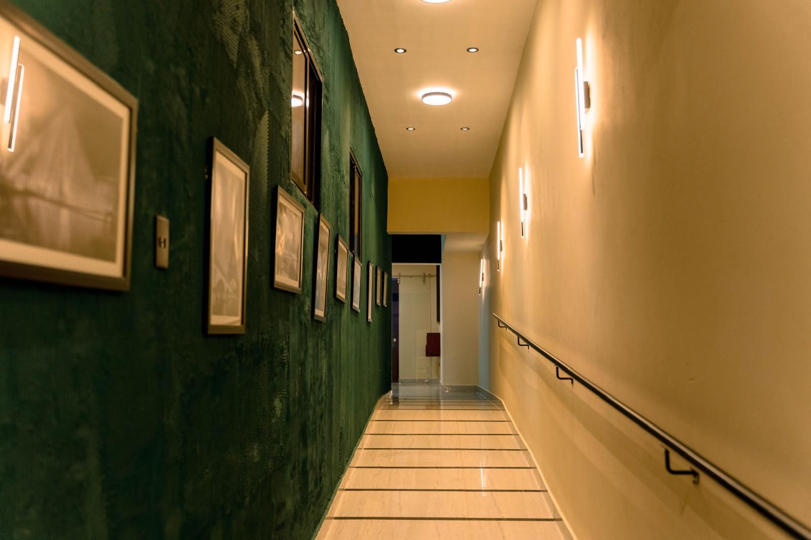 Pasillo de entrada con pared verde y cuadros enmarcados