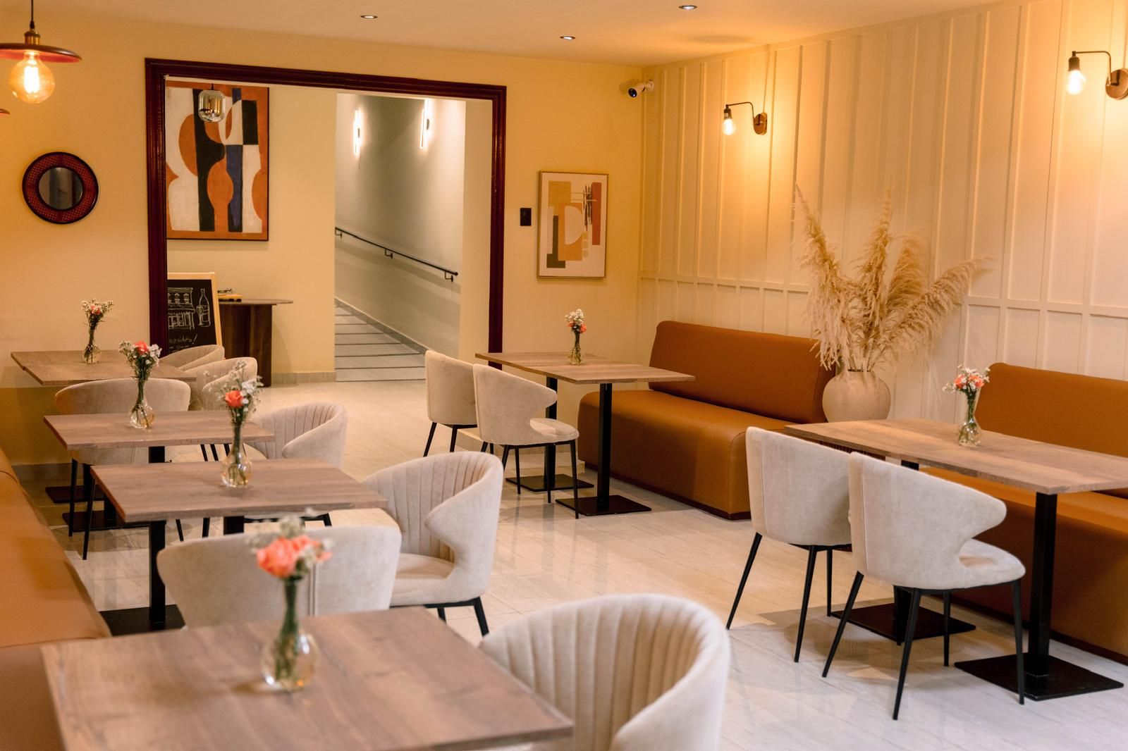 Comedor con mesas de madera, sillas tapizadas y obra en las paredes